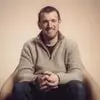 Portrett av Gareth Oates, smilende i en lenestol