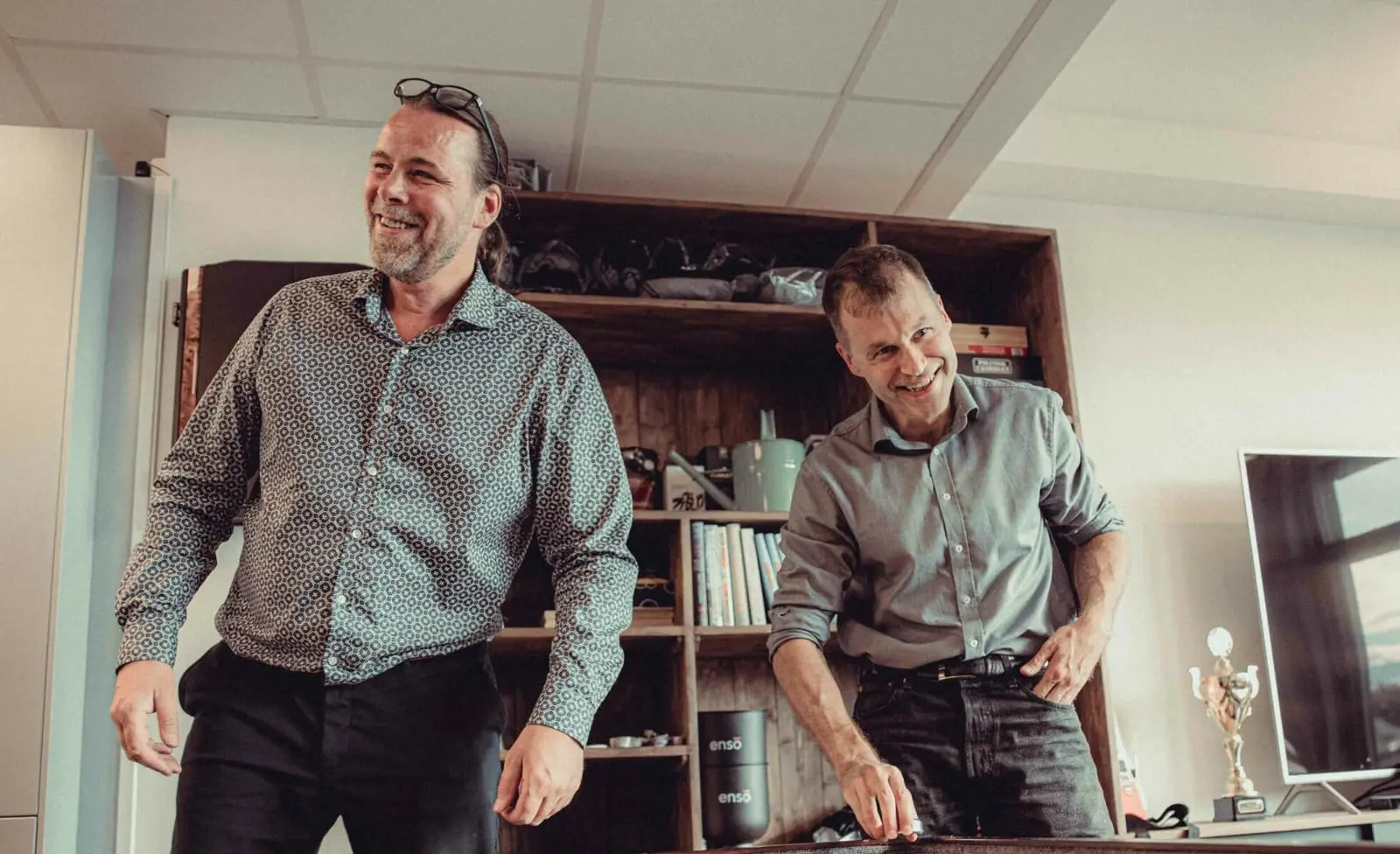 To kolleger ler mens de spiller et bordspill på kontoret