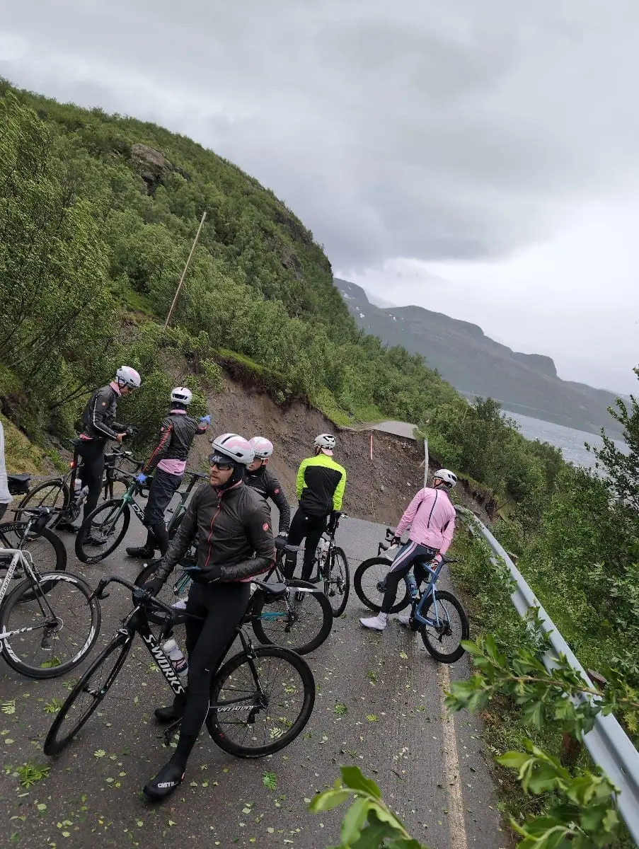 Syklister stopper der et jordras har tatt med seg veien langs en fjellside